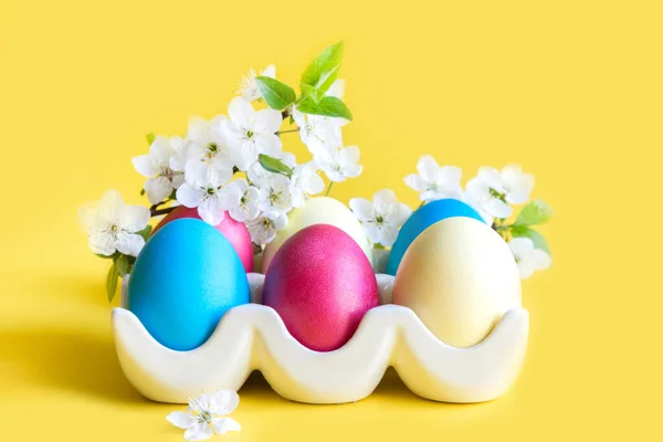 Színes tojások tavaszi virágokkal a sárgán. Húsvét. Tavasz. Közelről.. — Stock Fotó