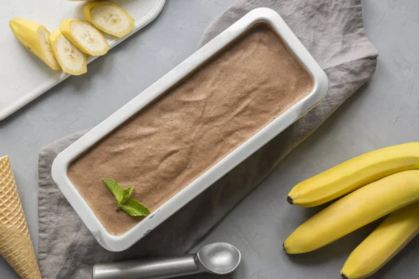 Banana and cocoa homemade ice cream in container on grey. — 图库照片