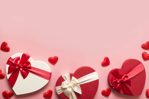 Valentijnsdag wenskaart. Rand van rode geschenkdozen hartvormig en veel hartjes op roze. Zicht van bovenaf. Ruimte voor tekst. — Stockfoto