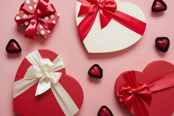 Valentines day greeting card. Pattern of red gift boxes heart shaped and chocolate sweets on pink. View from above. — 스톡 사진