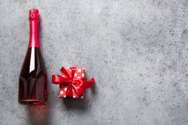 Sevgililer günü kartı. Bir şişe köpüklü gül şarabı ve gri üzerine hediye kutusu. Üst Manzara. Metin için boşluk.