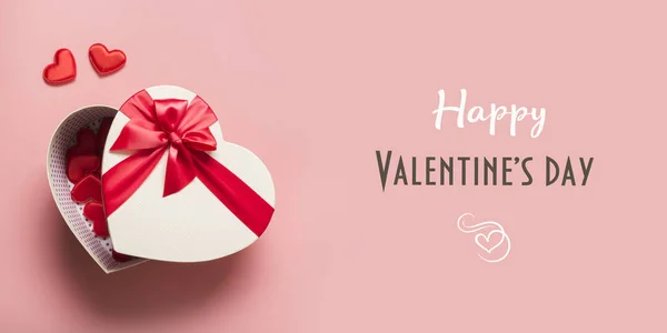 Tarjeta de felicitación de San Valentín. Caja de regalo roja y corazones en rosa. Banner. Vista desde arriba . — Foto de Stock