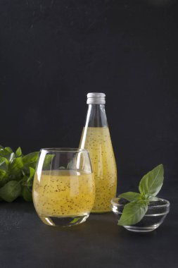 Blue cocktail with basil seeds and tropical orange juice in glass on black. Close up.