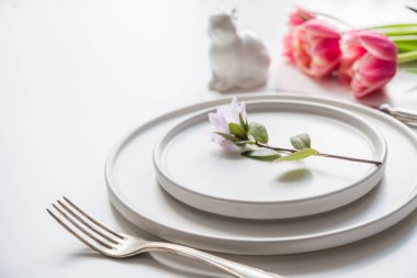 Easter dinner. Table setting with pink tulip, eggs on white table. Close up.