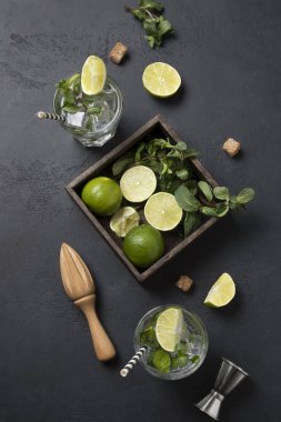 Mojito Kokteyl Malzemeleri, kireç, nane, su, siyah masa üzerindeki jigger. Yukarıdan bak. Dikey biçim.