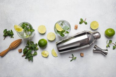Mojito kokteyl malzemeleri, limon, nane şekeri, karıştırıcı, gri ışıklı masa üzerindeki jigger. Yukarıdan bak. Yatay format. Boşluğu kopyala