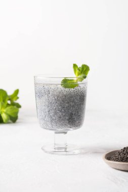 Sağlıklı detoks içeceği ve beyaz arka planda fesleğen tohumları. Dikey format. Kapat..