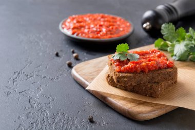 Bir dilim çavdar ekmeği ve ev yapımı makarna ayvar. Sebze sosu ya da siyah üzerine fırında kırmızı dolma biber havyarı. Balkan aperatifleri mutfağı. Kapat..