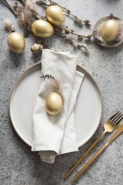 Elegant Easter table setting with golden eggs on grey stone table. Top view. clipart