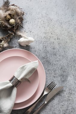 Paskalya sofrasında pembe tabak, tavşan ve bıldırcın yumurtası var. Zarif bir akşam yemeği. Üst Manzara. Dikey kompozisyon. Boşluğu kopyala.