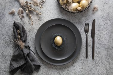 Gri masa üzerinde siyah ve altın desenli Paskalya masası. Üst Manzara. Mutlu bayramlar. Yemek servisi..
