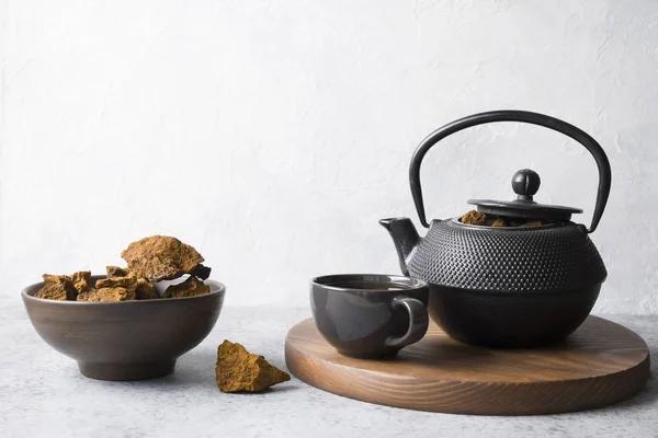 Organic Chaga tea in cup. Trendy Russian healthy infusion from birch mushroom on light background. Close up. Horizontal