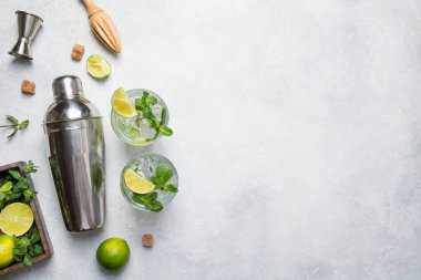 İçindekilerle mojito kokteyli, kireç, nane şekeri, sallama, jigger, gri ışık masasında tokmak. Yukarıdan bak. Yatay format. Metin için boşluk.