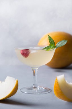 Kavunlu limonata, cam süslemeli ahududu, gri taş masada. Dikey format. Kapat..