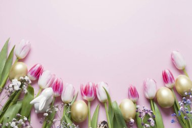 Pembe lalelerden, altın yumurtalardan ve pastel pembeden yapılmış tavşanlardan oluşan Paskalya çerçevesi. Kopyalama alanı olan üst görünüm. Mutlu Paskalyalar. Tebrik kartı.