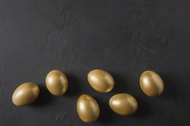 Siyah üzerine tavuk renginde altın yumurta. Paskalya yaratıcı karanlık kavramı. Üst Manzara. Düz yatıyordu. Kopyalama alanı olan en küçük bileşim.