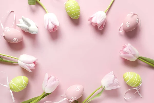 Cornice pasquale di fiori rosa freschi, uova colorate e coniglietto su rosa. Vista dall'alto, copiare spazio. Buona Pasqua. Biglietto d'auguri . — Foto Stock