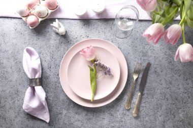 Gri taştan masasında taze pembe lale olan Paskalya sofrası. Üst Manzara. Zarif bir akşam yemeği..