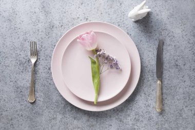 Gri taş masadaki pembe laleli Paskalya sofrası. Üst görünüm.