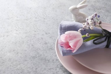 Pembe lale ve gri üzerine mor dekoru olan zarif bir bahar masası. Paskalya yemeği. Kapat..
