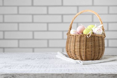 Beyaz tuğla duvarda Paskalya yumurtaları olan sepet. Metin veya tasarım için boşluk.