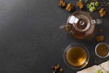 Cam bardakta Chaga içeceği ve siyah çaydanlık. Üst Manzara. Metin için boşluk.