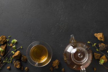 Cam bardakta mantar Chaga ve siyaha çaydanlık. Mesaj için yer var. Sağlıklı içecek. Yukarıdan bak. Koronavirüs sırasında bağışıklığı arttırmak için kullanışlı kahve alternatifi.