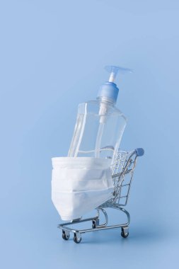 Koruyucu maskeli dezenfekte jeli market arabası. Coronavirus salgını sırasında alışveriş yapmanın tehlikeleri kavramı COVID-19.