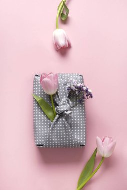 İlkbahar çevre dostu hediye. Gri tekstile sarılmış. Pembeye lale çiçeği dekoru takılmış. Sürdürülebilir bir hediye. Sıfır kayıp. Geleneksel Japon Furoshiki tarzı. Yukarıdan görüntüle.