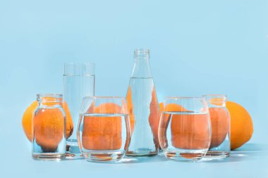 Turuncu turuncu turuncu, mavi bardaklarda sıvı suda bozulur. Kapatın. Yaratıcı tropikal konsept.