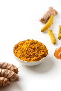 Kavanozda Curcuma tozu ve beyaz arka planda taze zerdeçal kökü. Sağlıklı baharat bağışıklığı. Kapatın. Doğal antiseptik. Dikey biçim.