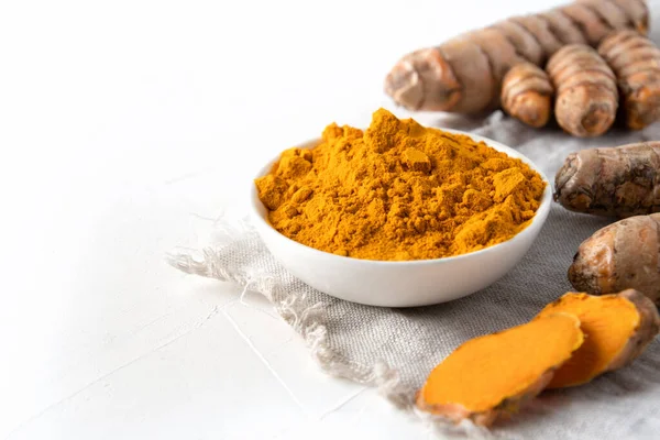 Kavanozda Curcuma tozu ve beyaz arka planda taze zerdeçal kökü. Mesaj için yer var. Sağlıklı baharat bağışıklığı. Kapatın. Doğal antiseptik..