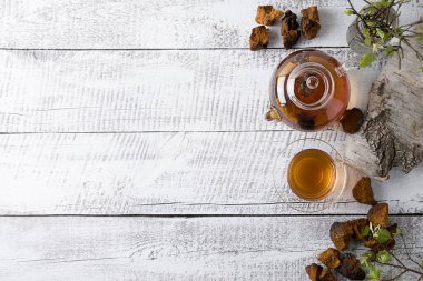 Kırsal beyaz tahta üzerinde cam çaydanlıkta organik Chaga mantarları eritiliyor. Moda, sağlıklı içecek. Yukarıdan bak. Virüs sırasında bağışıklığı arttırmak için kullanışlı kahve alternatifi.