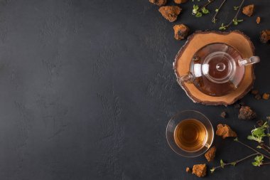 Cam bardakta Chaga içeceği ve siyah çaydanlık. Mesaj için yer var. Sağlıklı Rus içeceği. Yukarıdan bak. Kullanışlı kahve alternatifi.