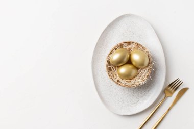 Beyaz masa üzerinde altın yumurtalar olan Paskalya sofrası. Yukarıdan bak. Metin için boşluk.