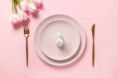 Paskalya minimumu masa dekore edilmiş tavşancık ve pembe laleler pembe üzerine. Zarif bir akşam yemeği. Üst görünüm.