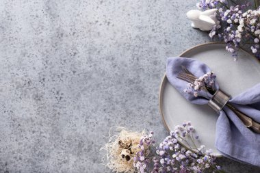 Gri plakalı Paskalya sofrası ve gri taş masada leylak dekoru. Zarif bir akşam yemeği. Üst Manzara. Mesaj için yer var. Pankart.
