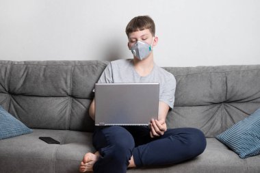 Genç kız Covid 19 virüsüne karşı korunmak için evde tıbbi maskeyle uzaktan eğitim okuyor. Coronavirus 'un önlenmesi.
