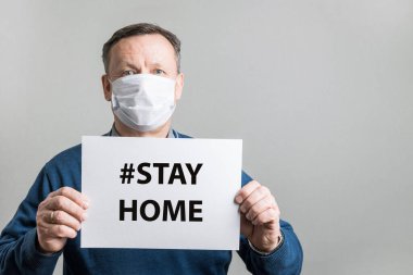 Koruyucu tıbbi maskeli yetişkin bir adam mesaj için beyazı tutuyor. Covid-19. Karantina konsepti. Coronavirus önleme.