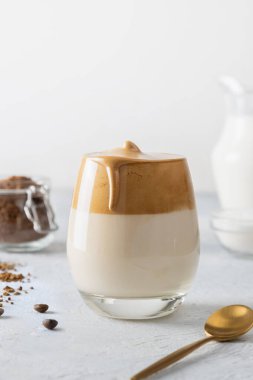 Kore bardakta Dalgona kahvesi içer. Beyaz arka planda köpüklü soğuk süt ve hazır kahve. Dikey çekim.