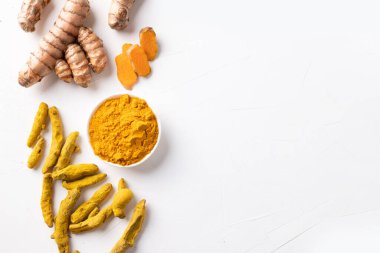 Kuru ve taze kök zerdeçal çerçevesi, beyaz beton arka planda sokağa çıkma yasağı tozu. Mesaj için yer var. Sağlıklı baharat bağışıklığı. Üst Manzara. Doğal antiseptik..