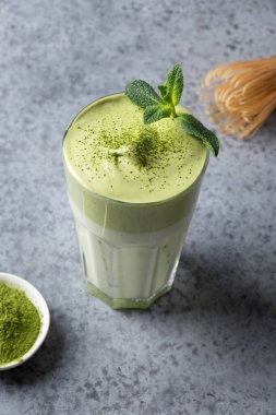 Dalgona Buzlu Matcha çayı. Çayla çırpılmış beyaz yumurta buzlu süte eklenir. Zamanda kendini izole eden enfes viral içecekler. Dikey biçim.