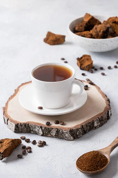 Chaga mushrooms and coffee on light background. Trendy healthy beverage. Vertical format. Close up.