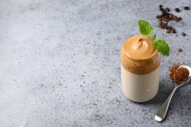 Dalgona köpüklü kahve, gri üzerine cam garnitür Melissa. Hazır kahve köpüklü Kore buzlu içeceği. Kapatın. Boşluğu kopyala.