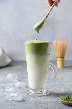 Dalgona Buzlu Matcha çayı, çırpılmış çay ve soğuk süt. Zamanda kendini izole eden enfes viral içecekler. Dikey biçim.