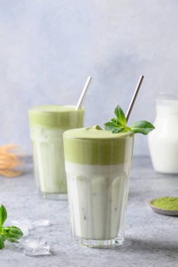 İki bardak Dalgona Matcha latte çayı ve çırpılmış çay. Kapatın. Dikey biçim.