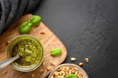 Fesleğen yapraklı ve fındıklı cam kavanozda pesto sosu. Yukarıdan bak. Kapatın. Metin için boşluk.