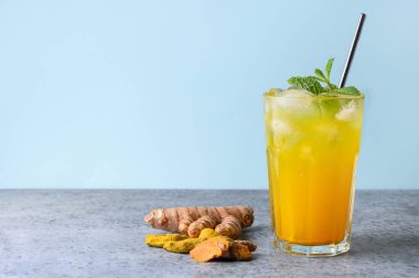 Bir bardak altın sütlü zerdeçal buzlu latte. Mavi arka planda Ayurvedic içki. Metin için boşluk.