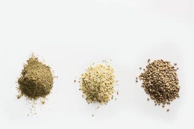 Üç yığın organik kenevir tohumu, un, beyaz üzerine izole edilmiş çekirdekler. Yukarıdan bak. Sağlıklı bileşen.