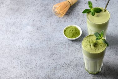 İki bardak Dalgona Buzlu Matcha çayı ve gri arka planda malzemeler. Uzayı kopyala Yukarıdan görüntüle.